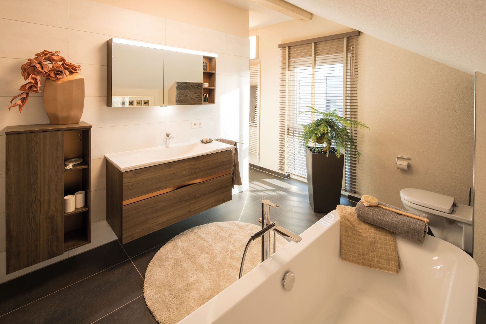 Modernes Badezimmer im FingerHaus NEO Musterhaus Günzburg mit Badewanne, Holzwaschtisch und großen Fenstern.