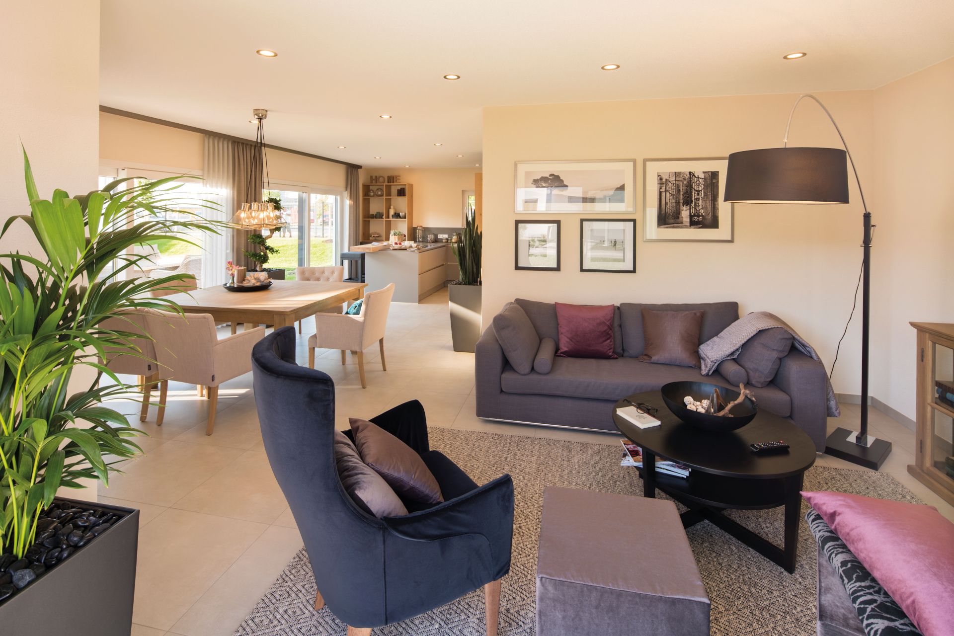 Helles Wohnzimmer im FingerHaus NEO Musterhaus Günzburg mit moderner Einrichtung, gemütlicher Sitzgruppe und Blick in den Ess- und Küchenbereich.