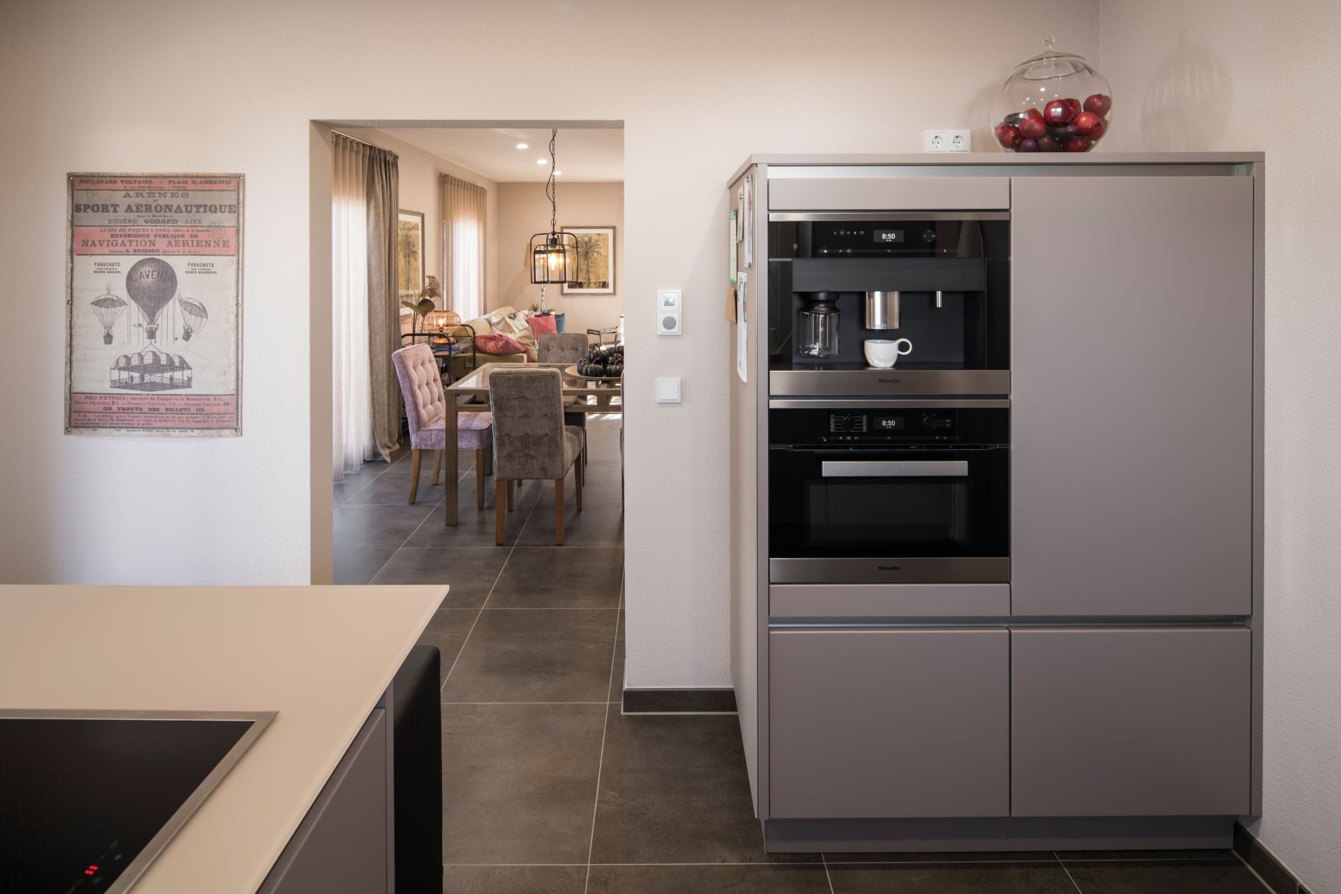 Moderne Küche im Musterhaus UNO 2.0 in Leipzig mit integrierten Einbaugeräten und Blick ins Esszimmer.