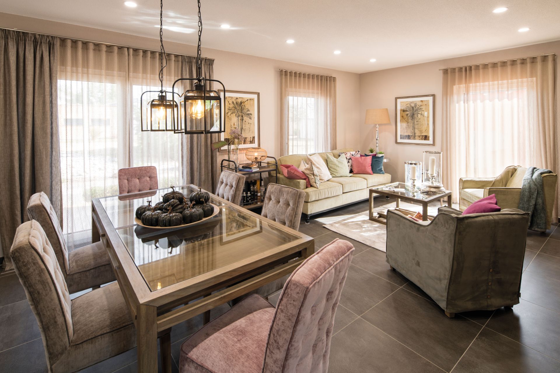 Wohn- und Essbereich im Musterhaus UNO Leipzig mit gemütlicher Sofaecke, Essplatz mit Glas-Esstisch und stilvoller Beleuchtung.