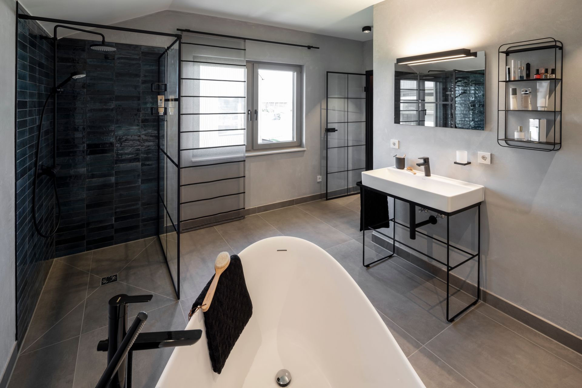 Modernes Badezimmer im FingerHaus ARTIS 400 Musterhaus Schwarzwald mit freistehender Badewanne, ebenerdiger Dusche, großem Waschtisch und stilvollem Design.