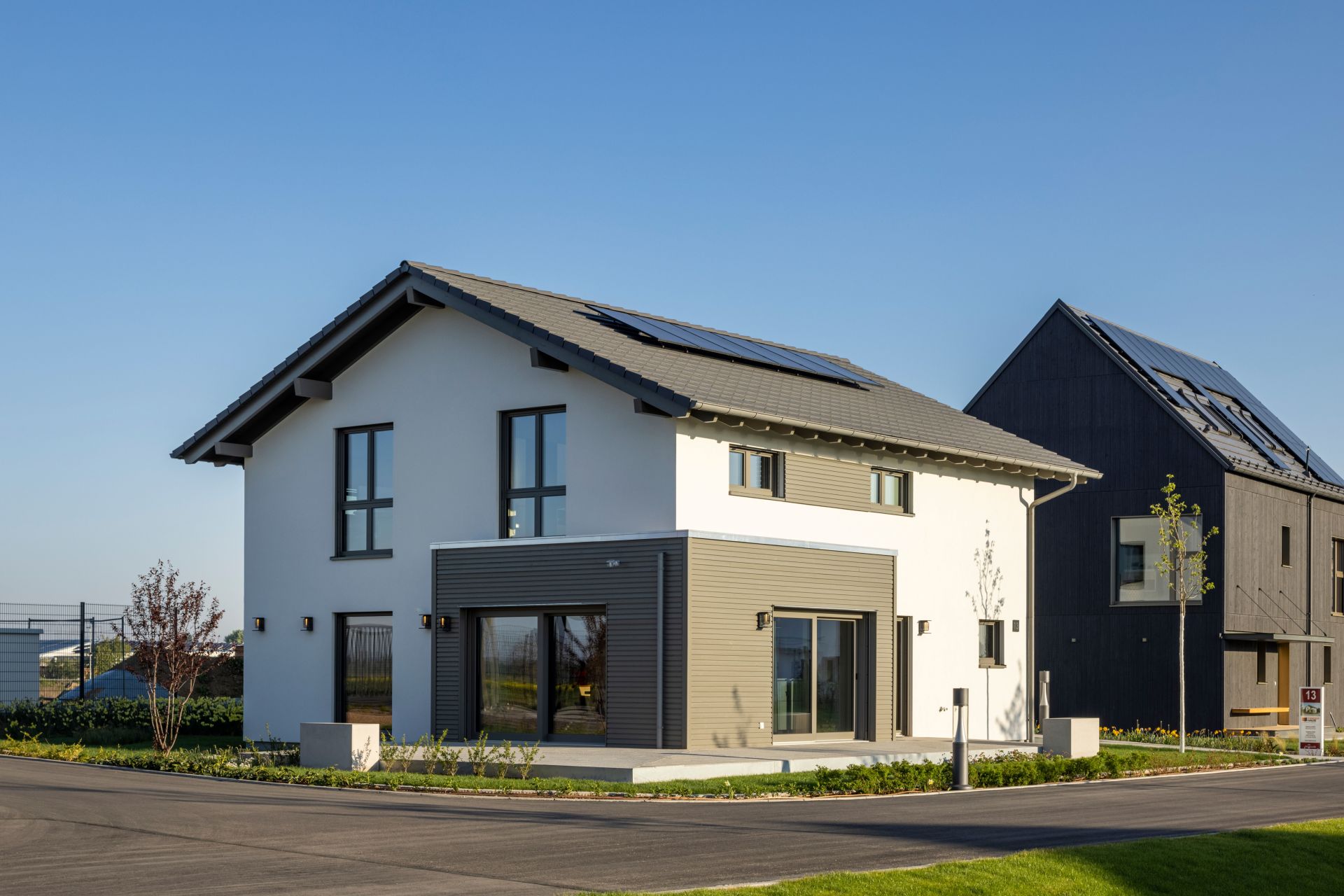 FingerHaus ARTIS 400 Musterhaus im Schwarzwald mit Satteldach, Photovoltaikanlage, weißer Fassade und modernen Holz-Elementen an den Fensterbereichen.