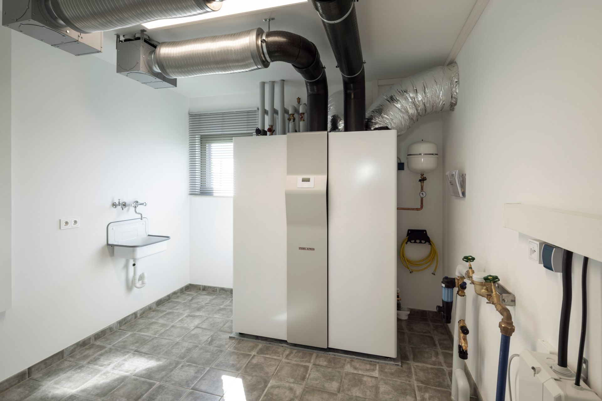 Hauswirtschaftsraum im FingerHaus ARTIS 400 Musterhaus Schwarzwald mit moderner Heizungs- und Lüftungsanlage, Waschbecken und funktionaler Ausstattung.