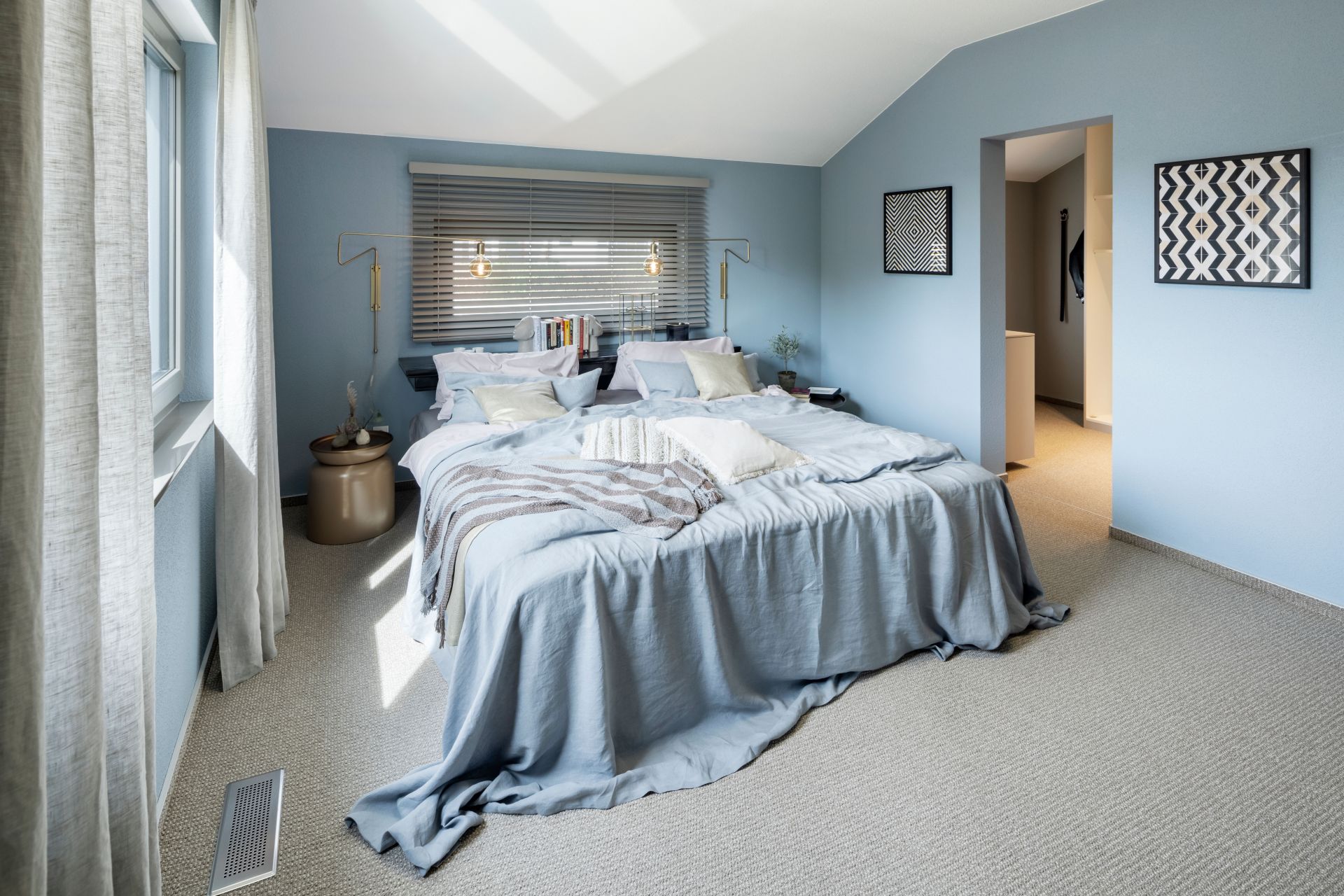 Helles Schlafzimmer im FingerHaus ARTIS 300 Musterhaus Würzburg mit blauen Wänden, großem Bett und Fensterfront.