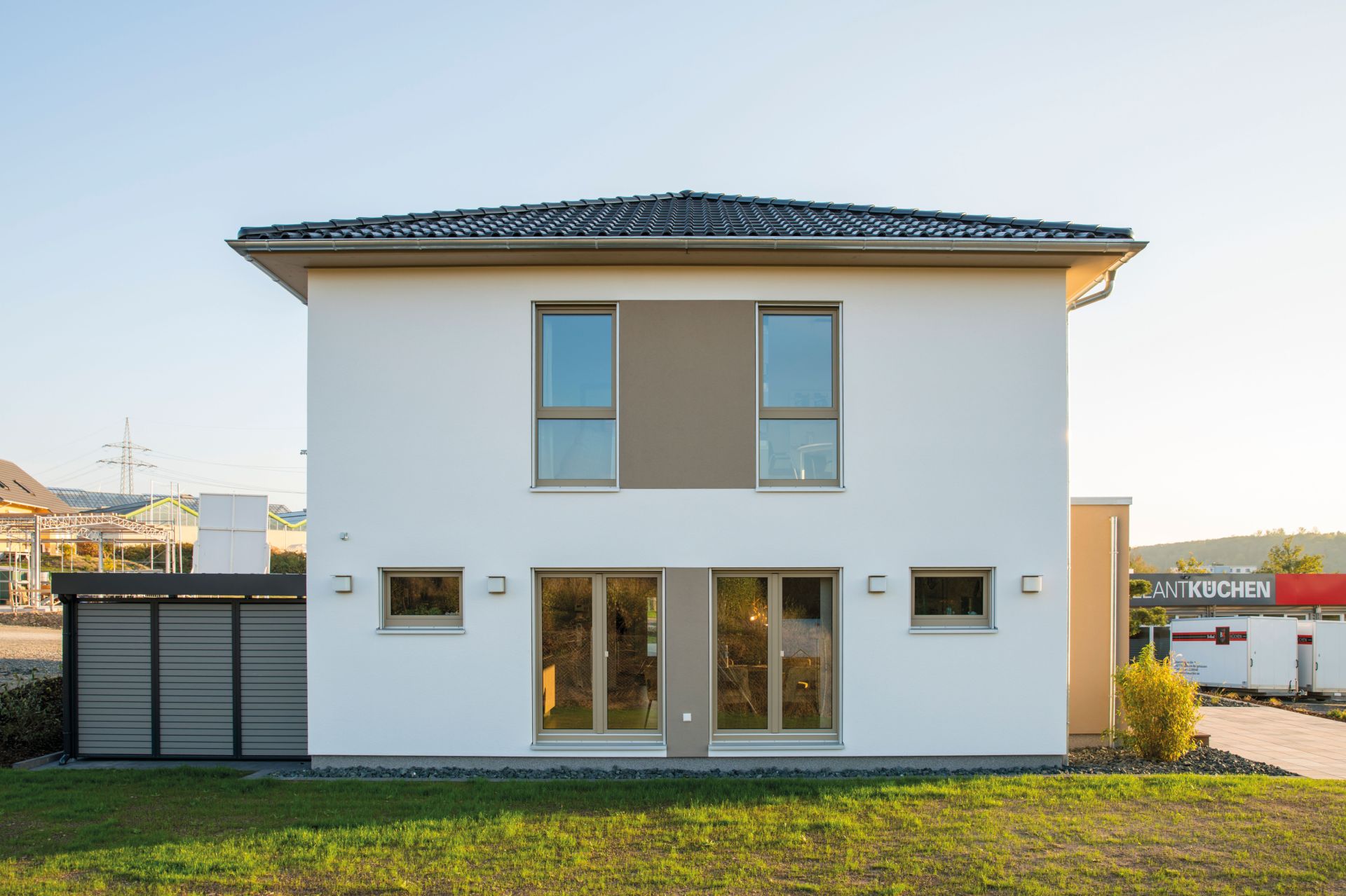 Rückansicht des Musterhauses MEDLEY 300 B in Kassel mit Walmdach, großen Fenstern und heller Putzfassade.
