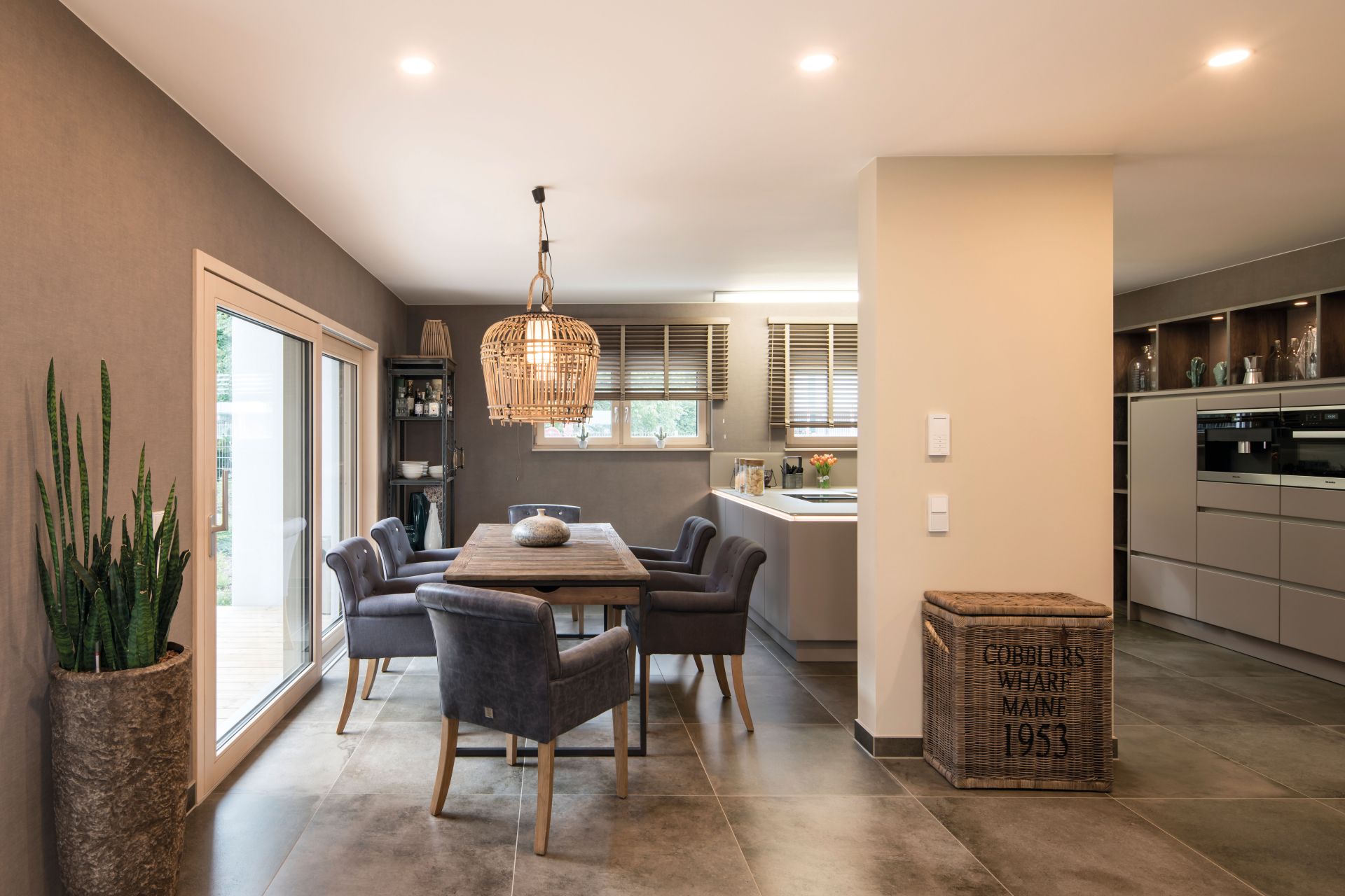 Essbereich im Musterhaus MEDLEY in Fellbach mit modernem Holztisch, gemütlichen Polsterstühlen und direktem Zugang zur Terrasse.