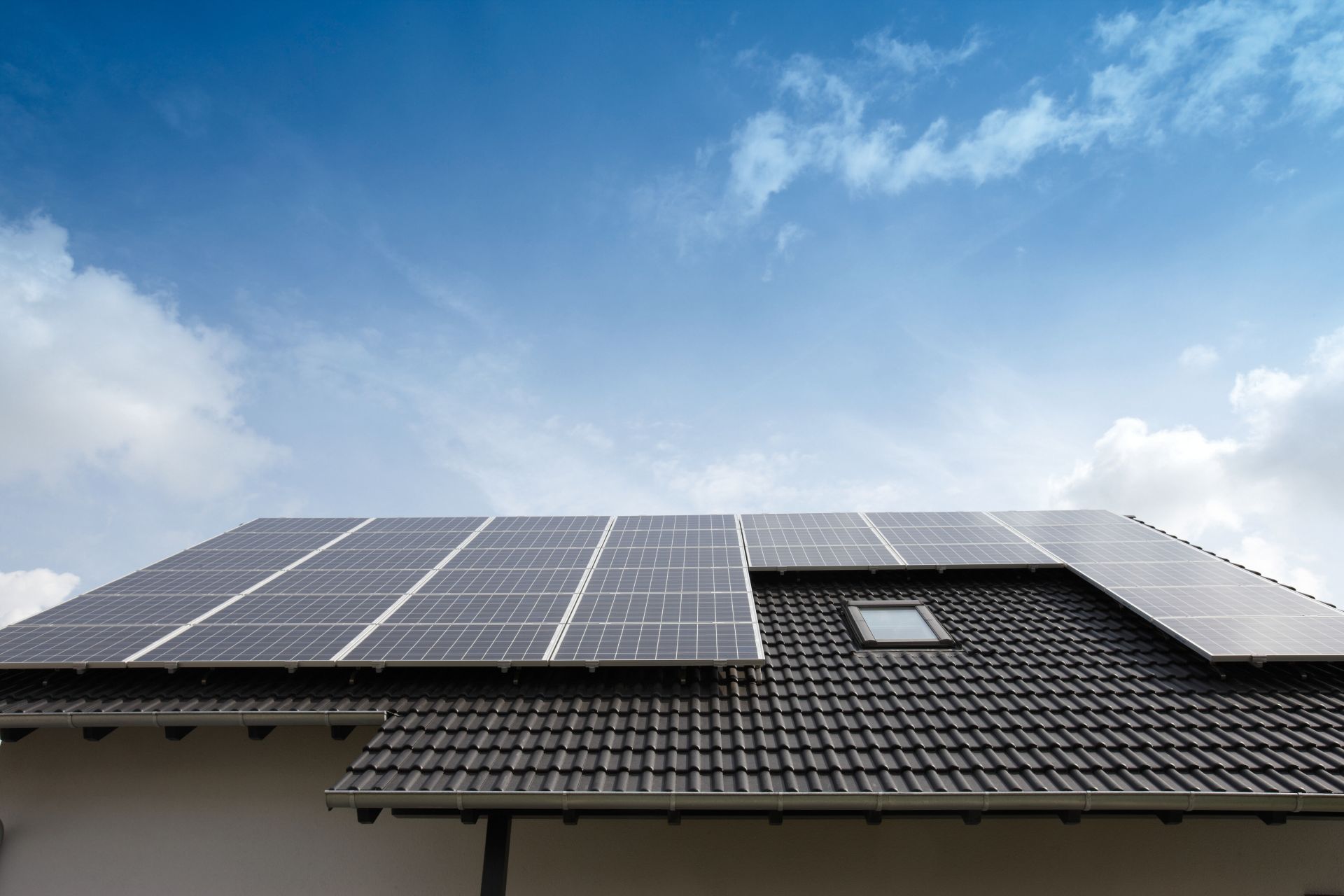 Dachansicht des Musterhauses VIO 400 in Köln mit großflächiger Photovoltaikanlage auf dem schwarzen Ziegeldach.