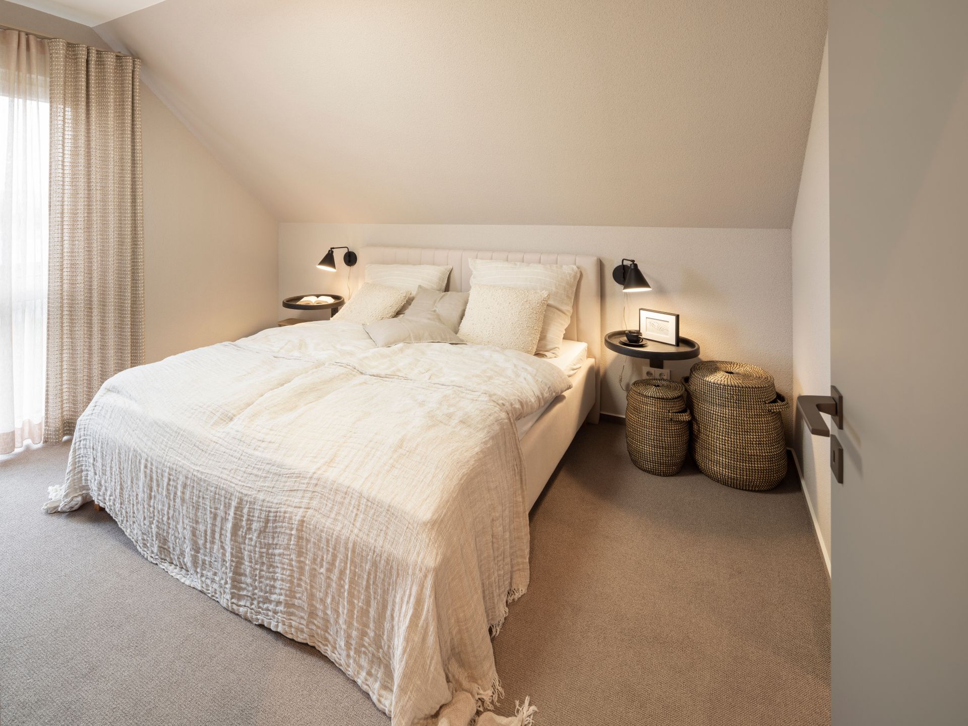 Gemütliches Schlafzimmer im Musterhaus JUNO 300 in Mülheim-Kärlich mit Doppelbett, Nachttischen und warmem Licht.