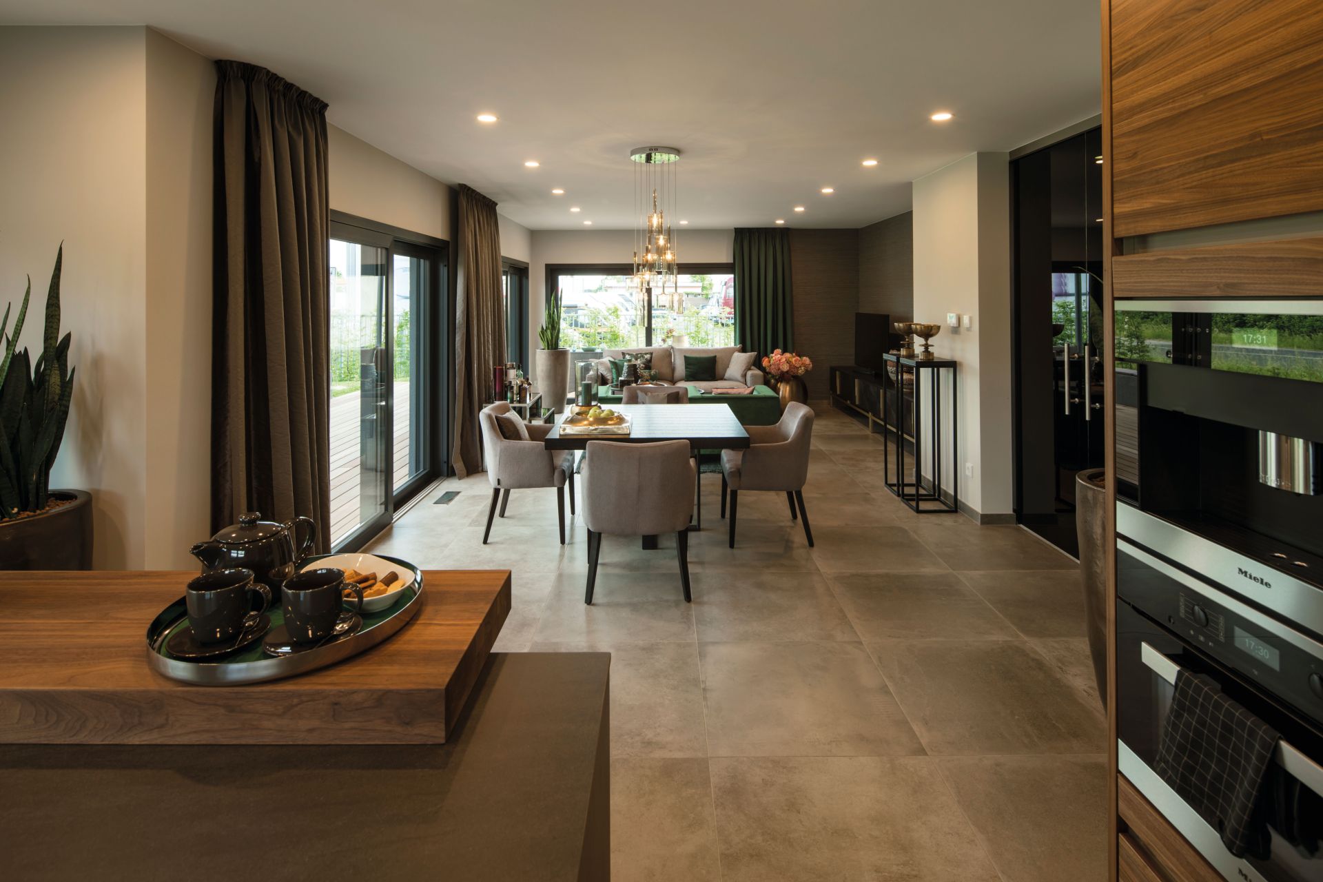 Offener Wohn- und Essbereich im Musterhaus MAXIM in Gießen mit eleganter Einrichtung, großen Fenstern und moderner Beleuchtung.