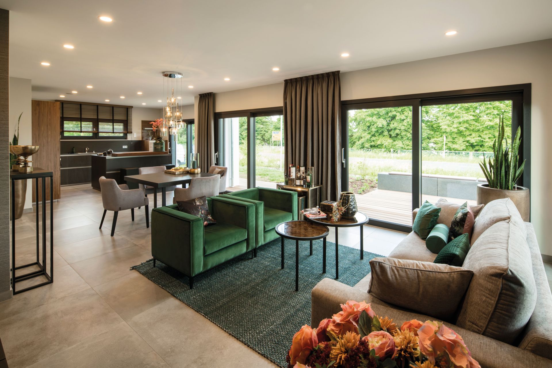 Offener Wohn- und Essbereich im Musterhaus MAXIM Gießen mit moderner Küche und bodentiefen Fenstern.