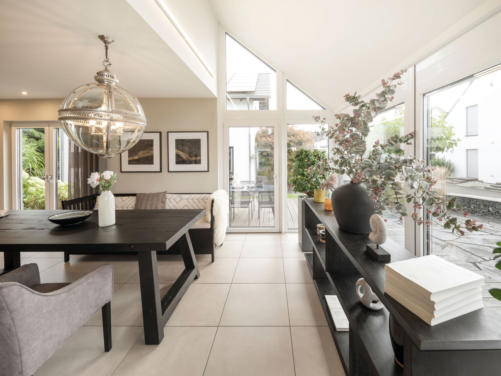 Heller Essbereich im Musterhaus NEO in Wuppertal mit großflächigen Fenstern, modernem Esstisch und stilvoller Dekoration im Wintergarten.