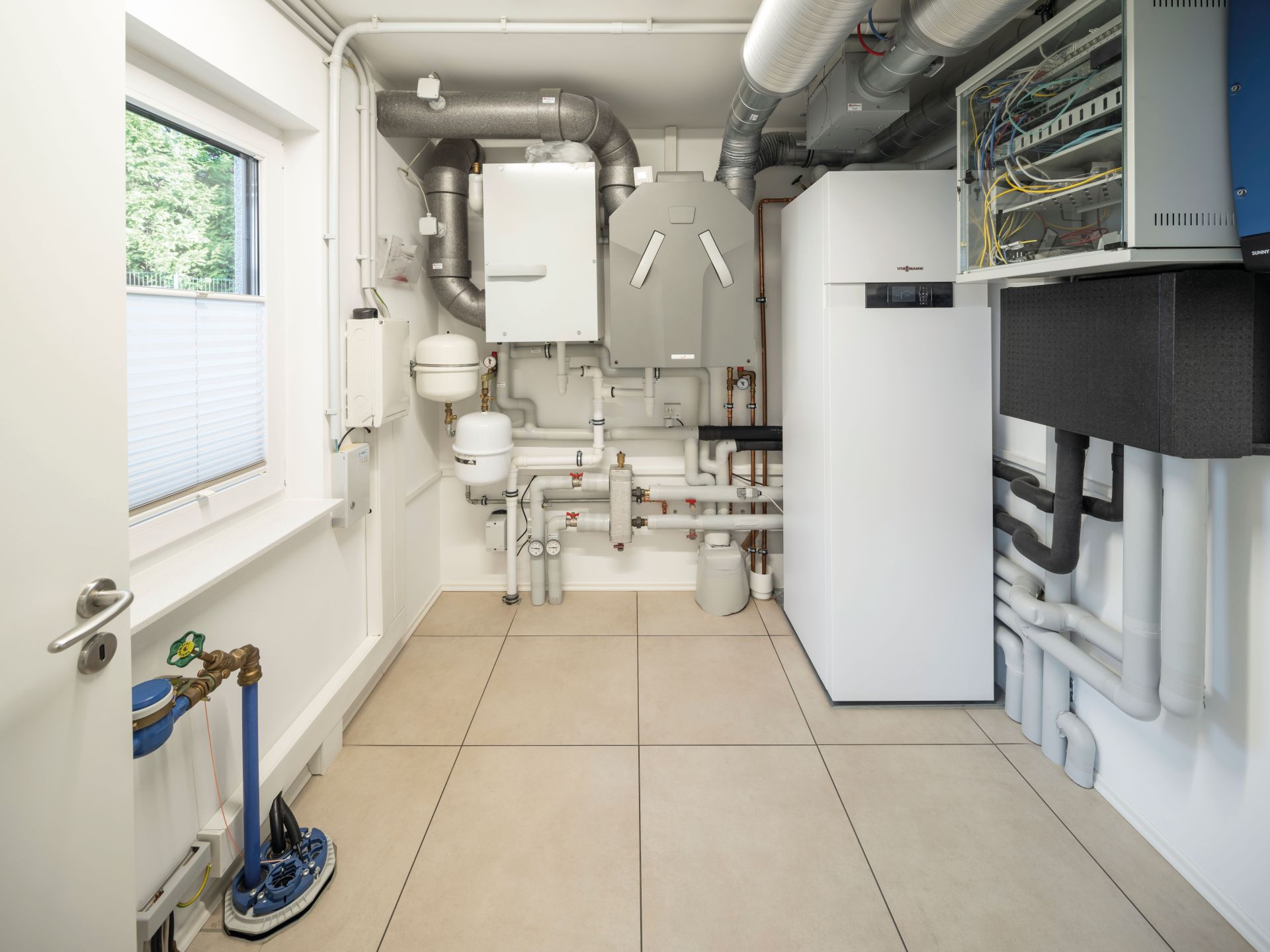 Hauswirtschaftsraum im Musterhaus NEO in Wuppertal mit moderner Heizungs- und Lüftungstechnik sowie praktischer Installation.