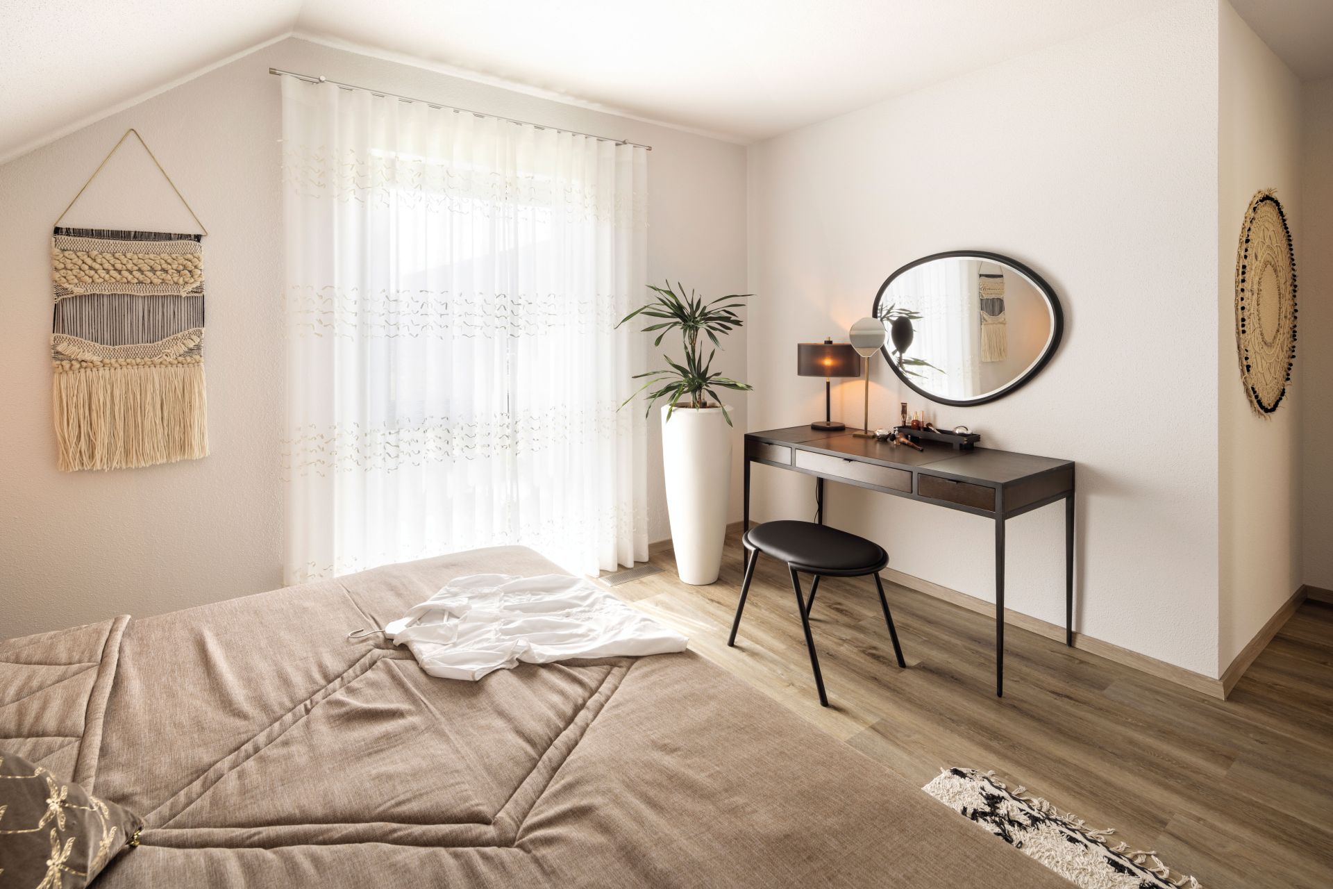 Helles Schlafzimmer mit Schminktisch, großem Spiegel und modernen Textilien im Musterhaus VIO in Köln.