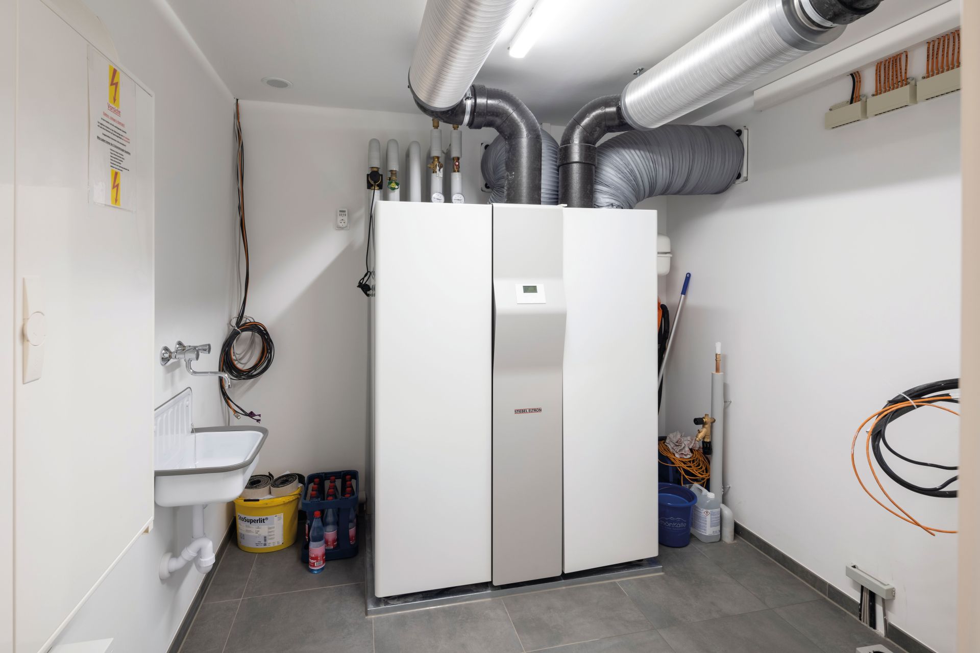 Hauswirtschaftsraum im Musterhaus TALO Fulda mit moderner Haustechnik, Lüftungsanlage und Waschbecken.