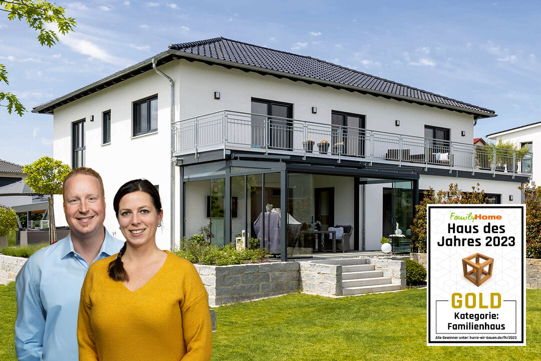 Zweigeschossiges, modern gestaltetes FingerHaus mit großzügigem Balkon und Wintergarten; davor ein Paar. Auszeichnung „Haus des Jahres 2023“ in Gold in der Kategorie Familienhaus.